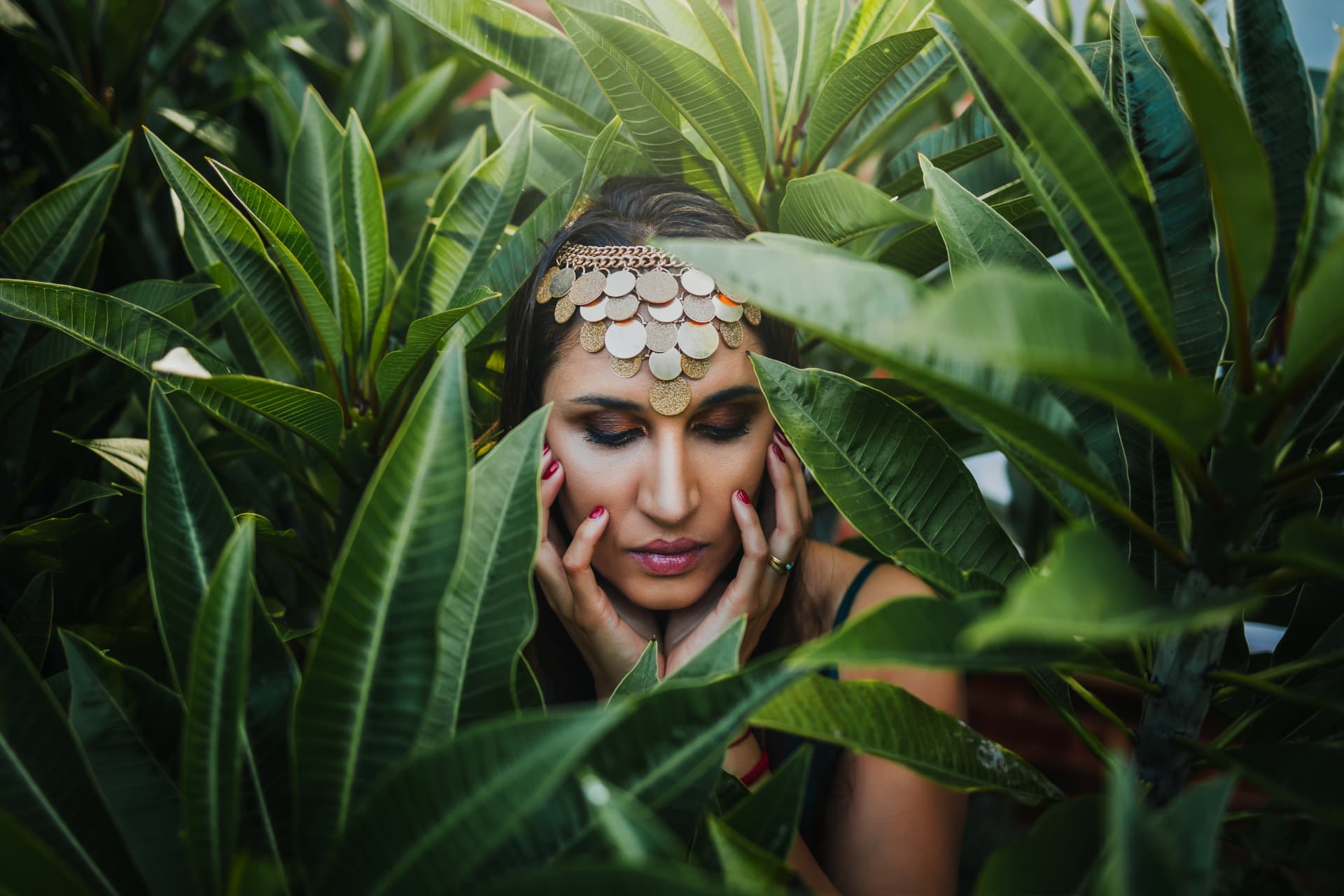 Noa resting among broad green leaves, eyes closed in stillness