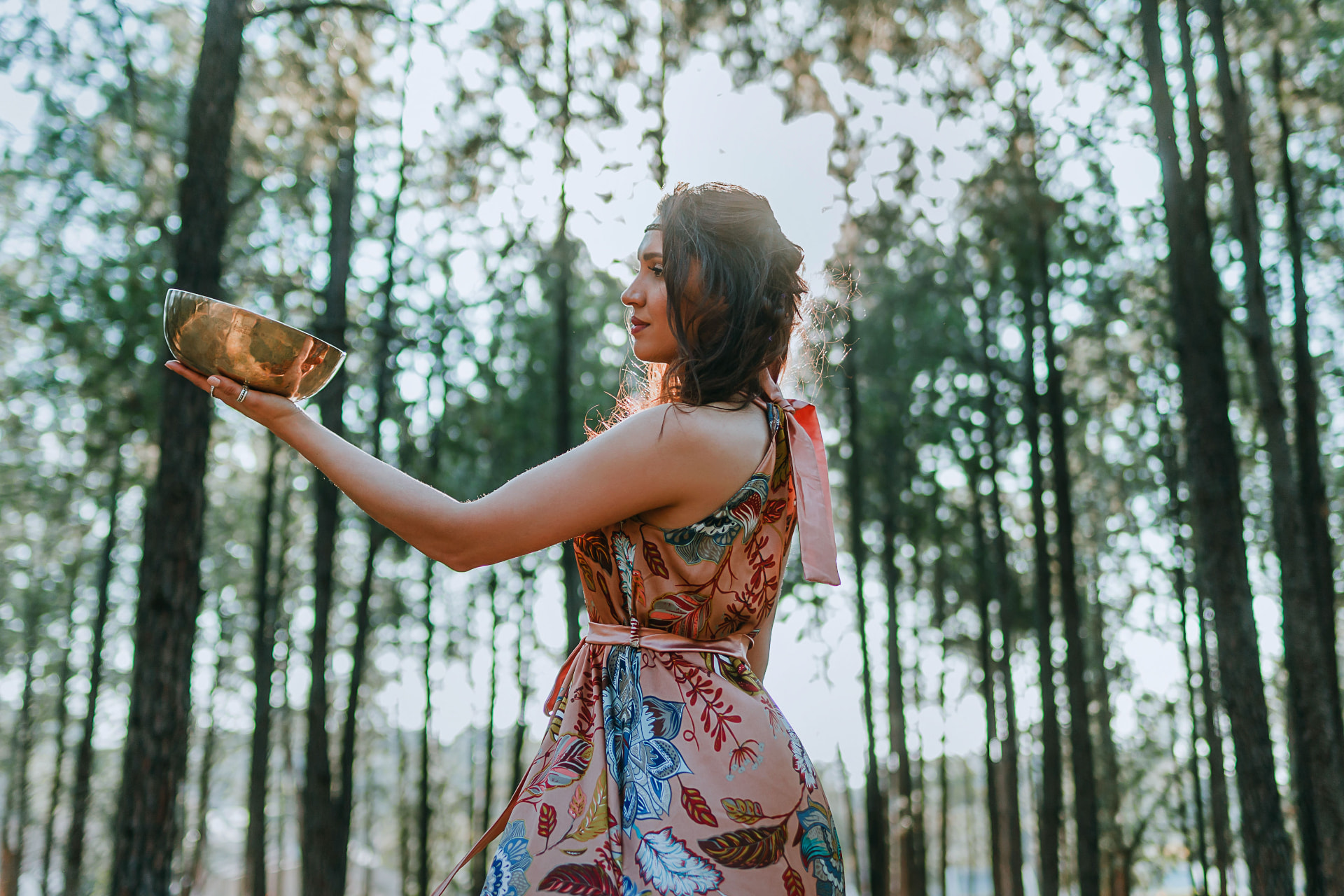 Noa offering a brass bowl in a sunlit forest