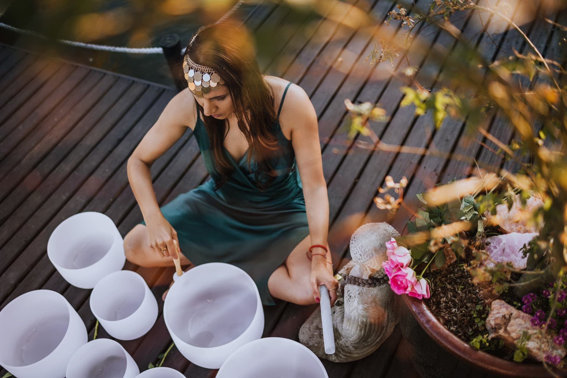 Noa playing crystal singing bowls on a deck at golden hour